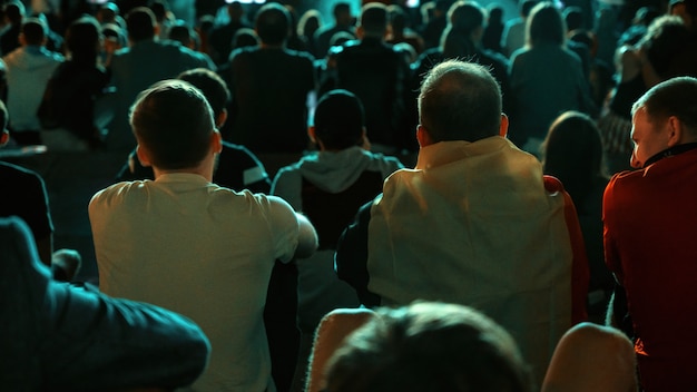 Pessoas sentadas assistindo futebol em um lugar público à noite