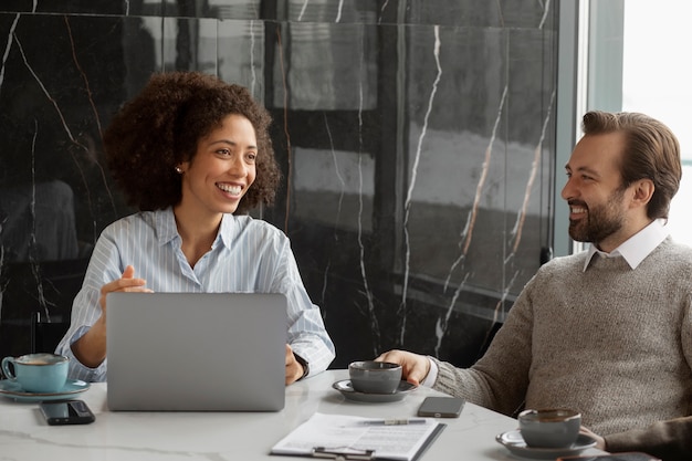 Pessoas sorridentes de tiro médio falando no trabalho