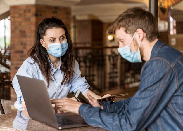 Pessoas trabalhando juntas em ambientes fechados usando máscaras médicas