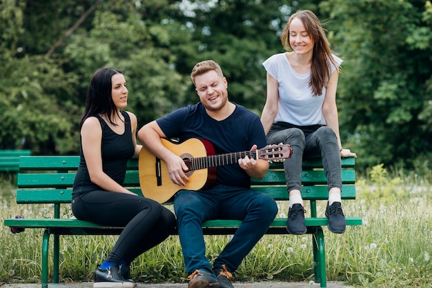 Pessoas Unidas relaxando no banco cantando e tocando guitarra