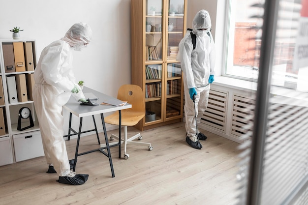 Pessoas usando equipamento de proteção para desinfetar uma área perigosa