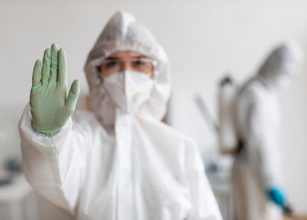 Foto grátis pessoas usando equipamento de proteção para desinfetar uma área perigosa