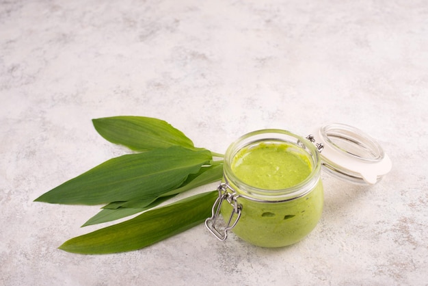 Pesto feito de pinhões de alho selvagem e queijo feta em um copo com folhas frescas em um texto branco