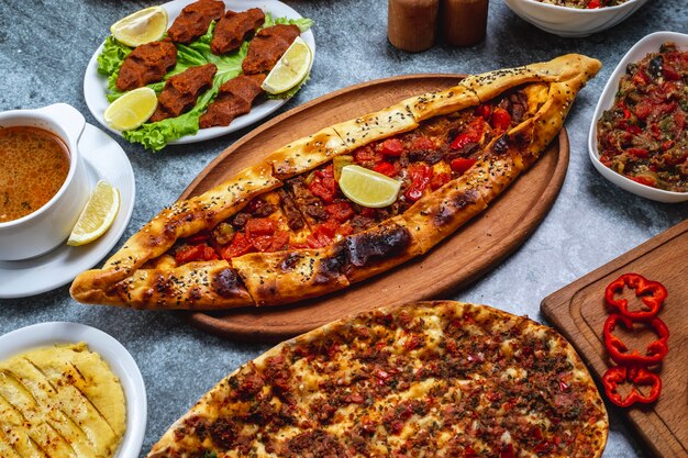 Pide de vista lateral com carne moída cebola pimenta fatia de limão e bife vegetariano tártaro em cima da mesa