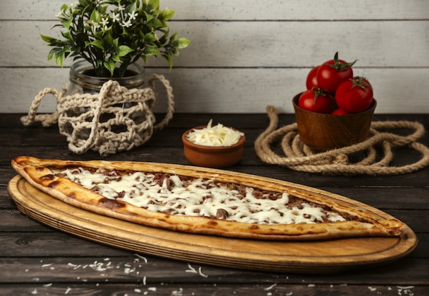 Pide tradicional turca com queijo e carne em uma placa de madeira