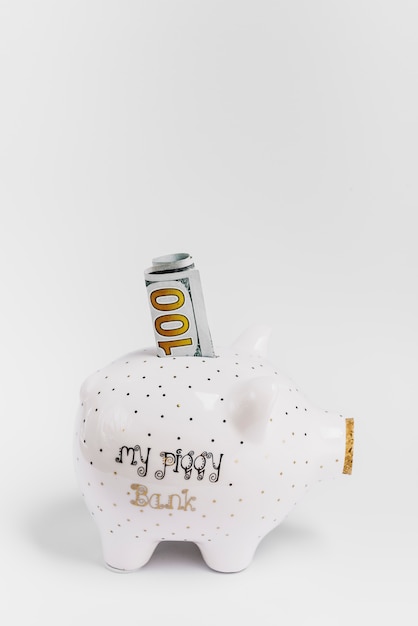 Piggybank com cem notas sobre fundo branco