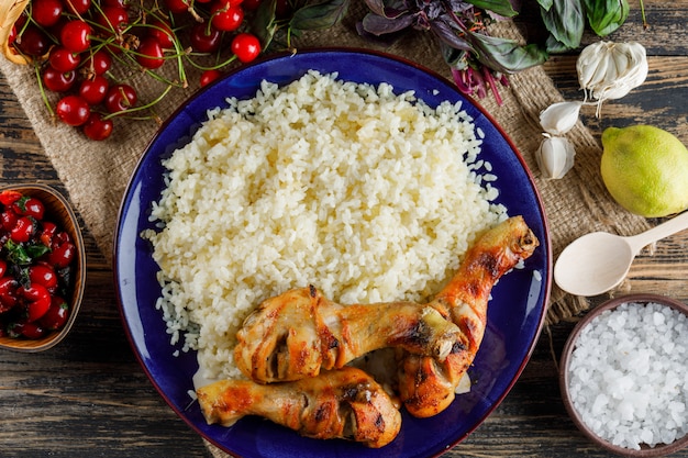 Pilaf com carne de frango, cereja, sal, limão, manjericão, alho em um prato na madeira e pedaço de saco.