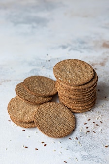 Pilha de biscoitos saborosos com sementes de gergelim e linho em fundo cinza lanche saudável