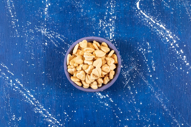 Pilha de biscoitos salgados em forma de coração colocados em uma tigela azul