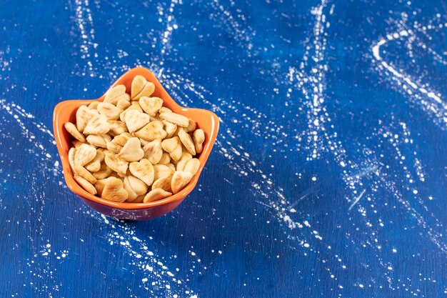 Pilha de biscoitos salgados em forma de coração colocados em uma tigela de laranja