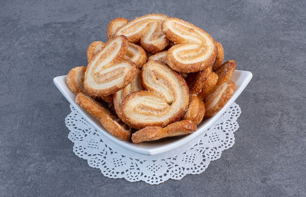 Pilha de deliciosos biscoitos em uma tigela branca.