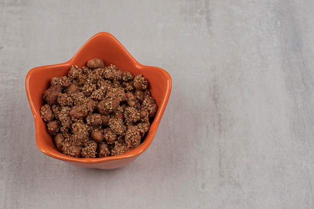 Pilha de doces com sementes de gergelim em uma tigela de laranja.