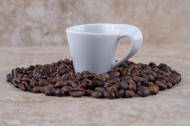 Pilha de grãos de café bem organizada em torno de uma xícara de café