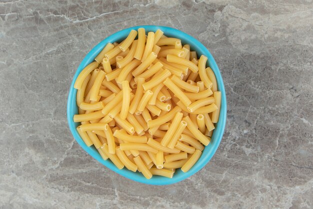 Pilha de macarrão cru na tigela azul