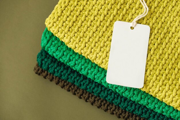 Pilha de material de malha de fios de cores marrons verdes amarelas com etiqueta de preço em branco