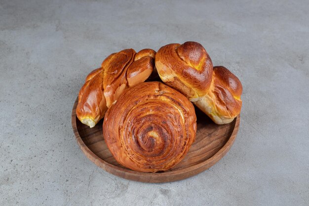 Pilha de pães doces, em uma pequena bandeja na mesa de mármore.