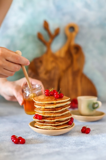 Pilha de panquecas caseiras com calda de mel e frutas.