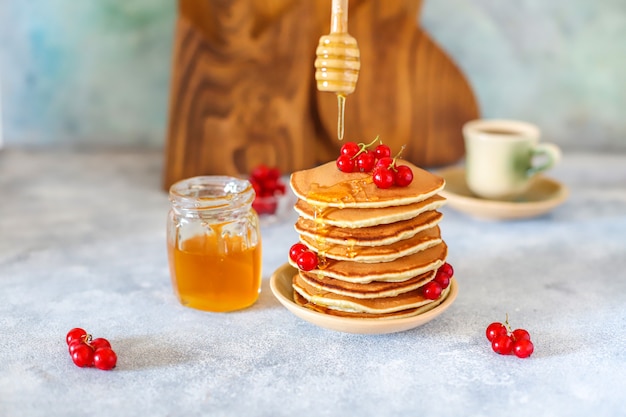 Pilha de panquecas caseiras com calda de mel e frutas.