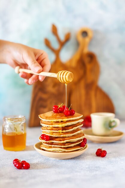 Pilha de panquecas caseiras com calda de mel e frutas.