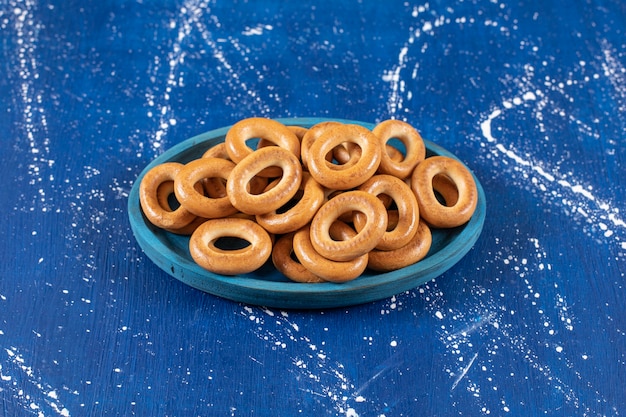 Pilha de pretzels redondos salgados colocados em um prato azul