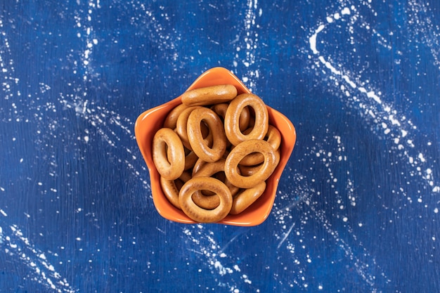 Pilha de pretzels redondos salgados colocados em uma tigela de laranja