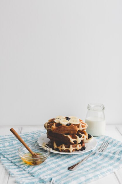 Pilha de waffles perto de mel e produtos lácteos