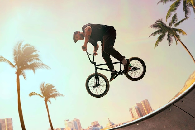 Piloto de bmx está realizando truques no skatepark no pôr do sol