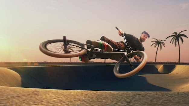 Foto grátis piloto de bmx está realizando truques no skatepark no pôr do sol