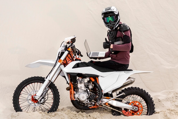 Piloto de moto com capacete segurando laptop