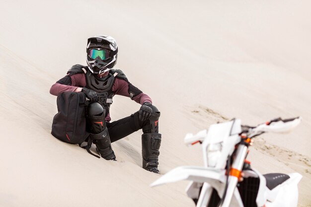 Piloto de moto elegante relaxante no deserto