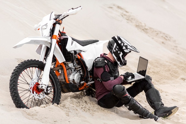 Piloto de moto navegando laptop no deserto