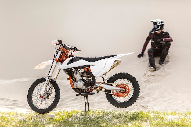 Foto grátis piloto elegante com moto no deserto