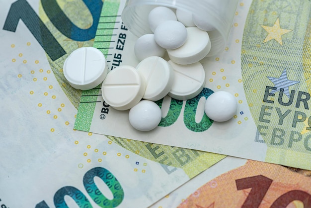 Pílulas ou cápsulas de remédios diferentes sobre notas de euro, custo caro da medicina.