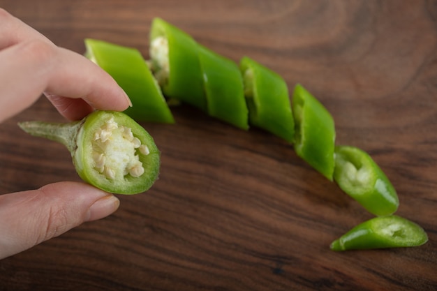 Pimenta picada e fatia de exploração de mão feminina.