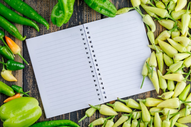 Pimentas com caderno aberto plana colocar em um de madeira