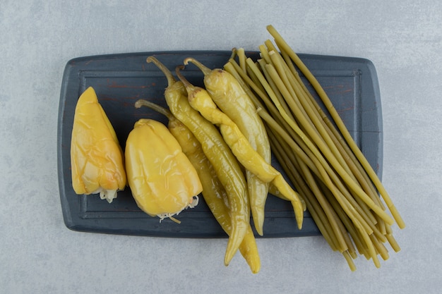 Pimentas e verduras em conserva no quadro escuro.