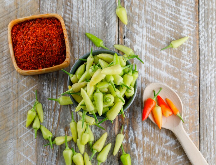 Foto grátis pimentas no mini balde e colher com flocos de pimenta vermelha plana colocar em um de madeira
