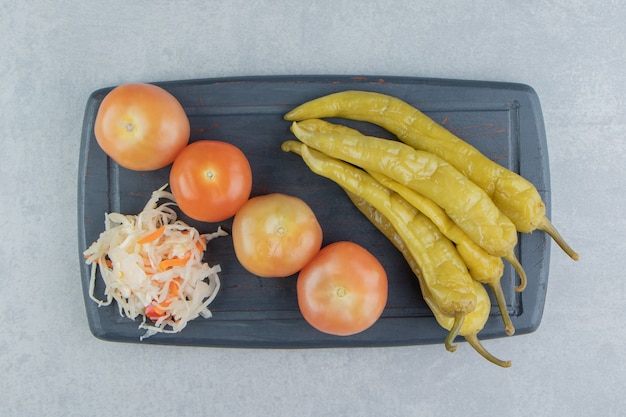 Pimentas, tomates e chucrute em uma placa na superfície de mármore