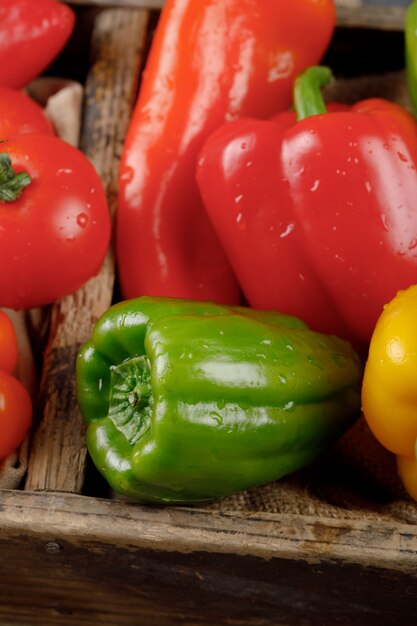 Pimentos verdes e vermelhos frescos em uma bandeja rústica.