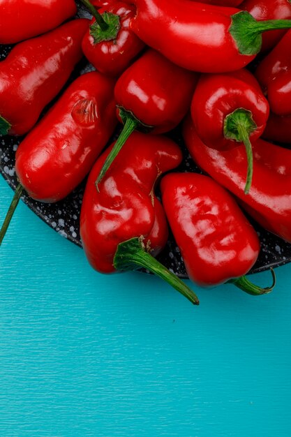 Pimentos vermelhos em um prato de cerâmica close-up em uma parede azul