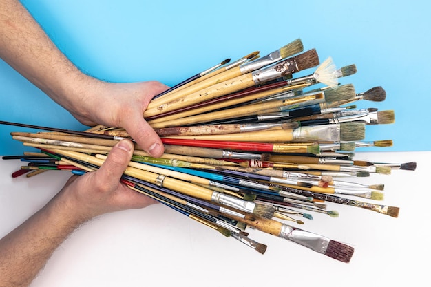 Foto grátis pincéis em mãos masculinas em uma vista superior de fundo colorido