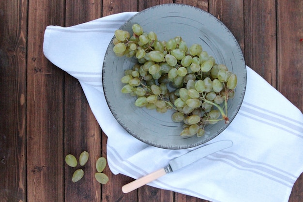 Pincel de vista superior de uvas verdes em um copo com uma faca na mesa