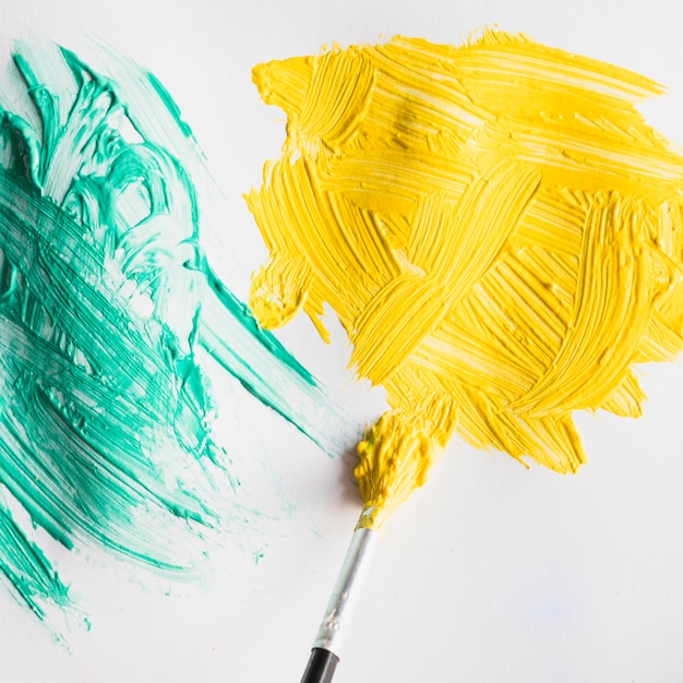 Pincelada de tinta verde e amarela na folha de papel branco