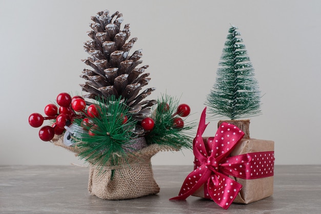 Pinha decorada com bagas de azevinho e um saco de presente na mesa de mármore.