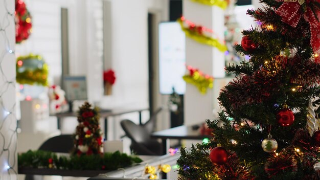 Pinheiro de Natal adorna com guirlandas e enfeites no escritório vazio. Previsões de receitas de negócios em telas de computador no Natal adornam locais de trabalho sem trabalhadores durante as férias de inverno