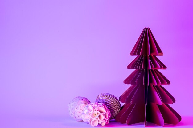 Pinheiro de papel com bolas de Natal em fundo azul com luz neon