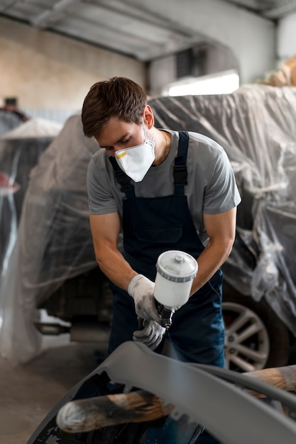 Foto grátis pintor masculino de macacão fazendo seu trabalho na loja de carros