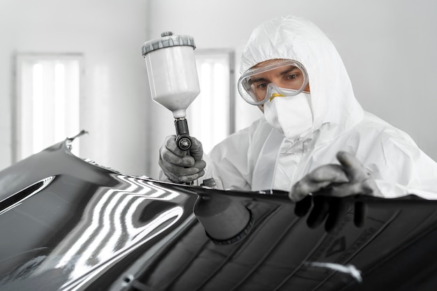 Foto grátis pintor masculino usando arma para pintar carro na loja