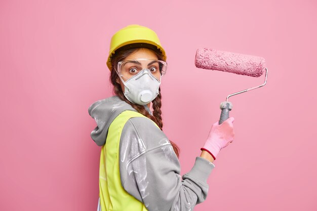 Foto grátis pintora surpresa se muda para uma nova casa ocupada fazendo reparos em suportes de rolo de pintura