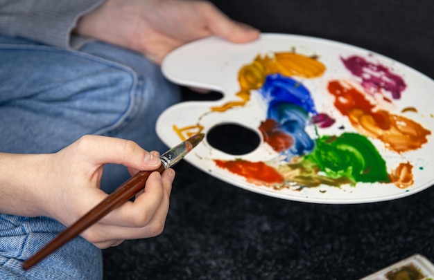 Pintura aproximada em uma paleta nas mãos femininas